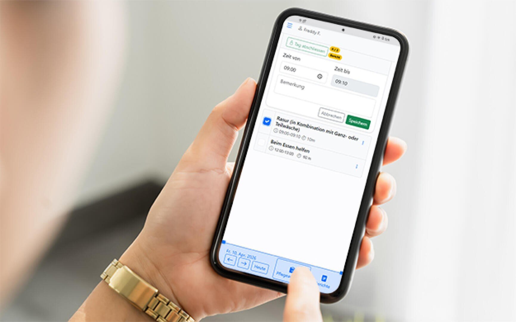 Une personne tenant un smartphone à la main et utilisant une application contenant du texte en allemand sur le thème des pauses au travail. L'écran affiche des options permettant de saisir la durée des pauses et d'ajouter des commentaires, tandis que des onglets et une barre de navigation sont visibles en bas de l'écran.